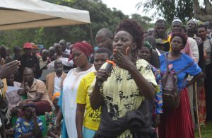 Holding the microphone; Robinah Nantumbwe with other claimants lining to address the MInister about their issues